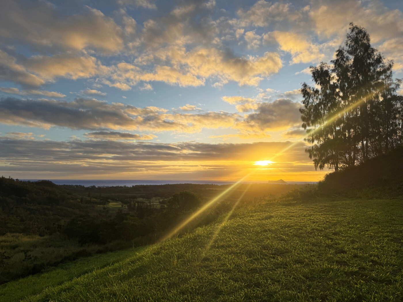 Golden sunrise over a lush two-acre property in Olomana Heights with views extending to the Waimanalo Bay coastline.